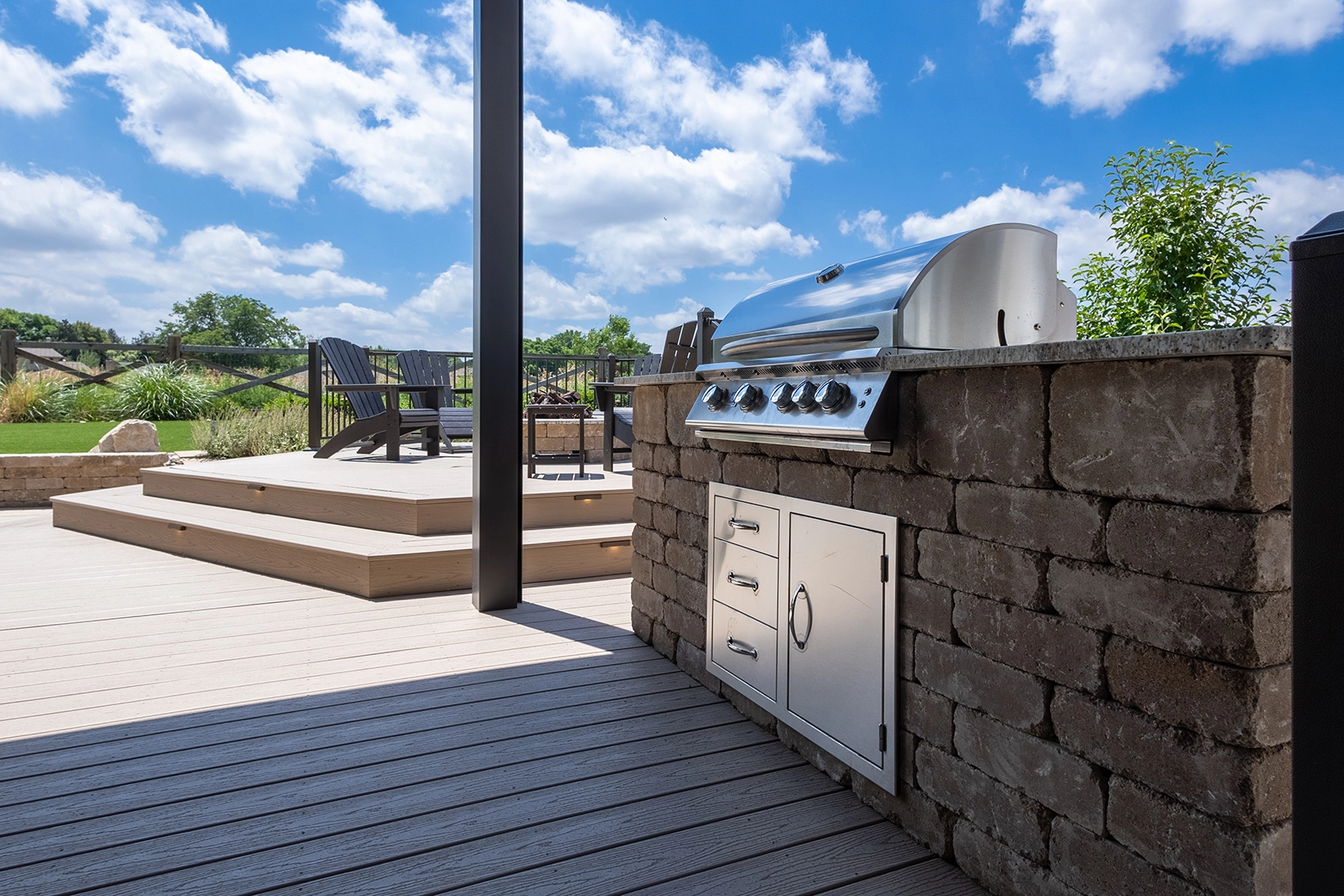Built-in stainless grill in a stone counter beside a composite deck