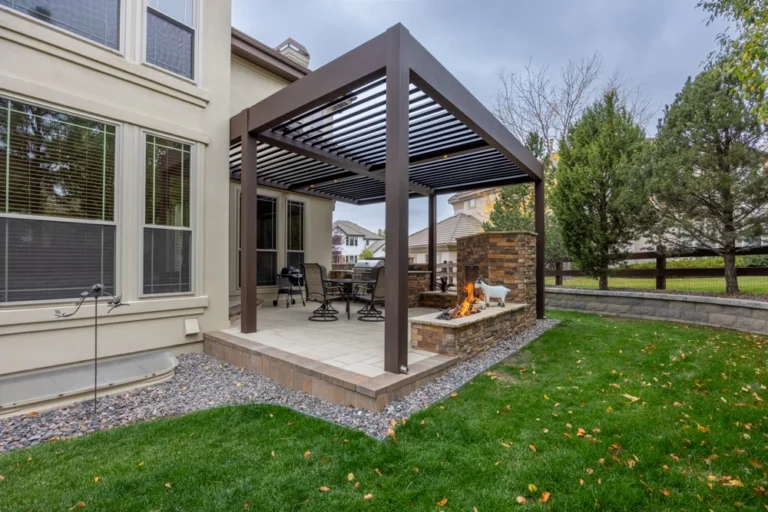Azenco aluminum pergola over a paver patio with a stacked-stone gas fireplace and outdoor dining set in a Colorado backyard