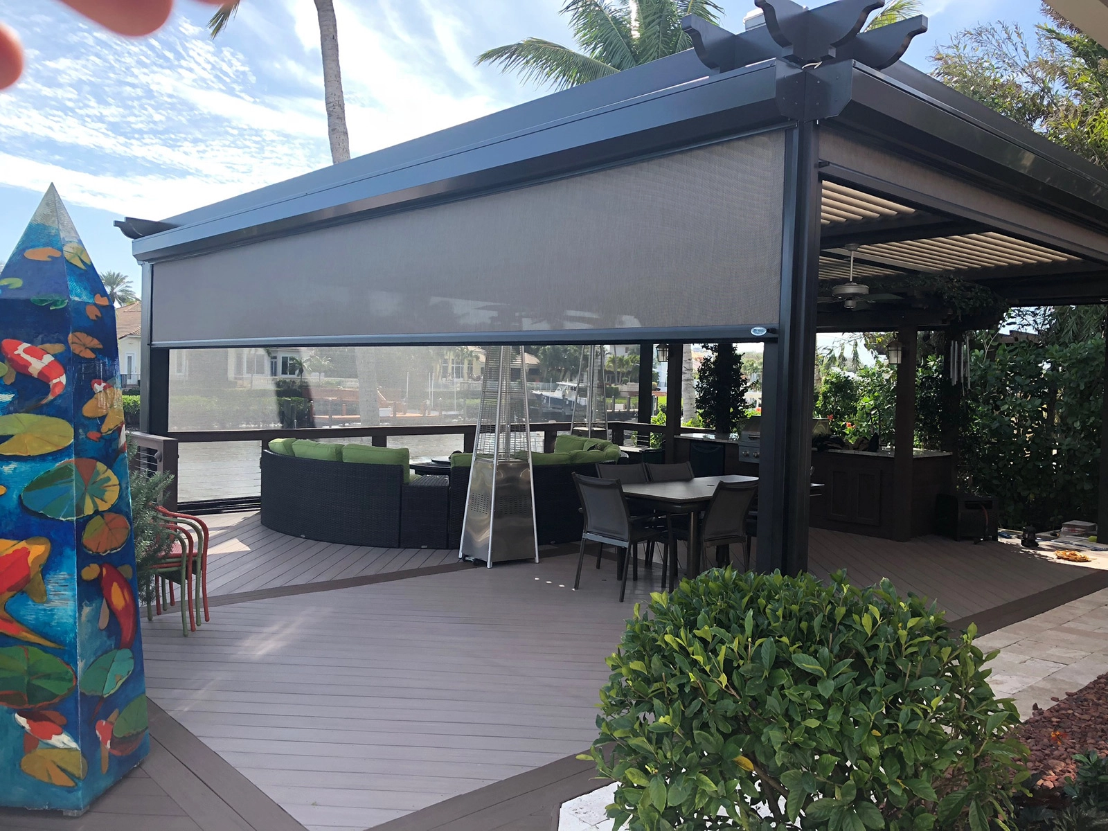 Motorized retractable screen lowered on a covered waterfront patio