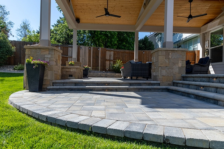 Curved paver patio with steps up to a covered pavilion with ceiling fans
