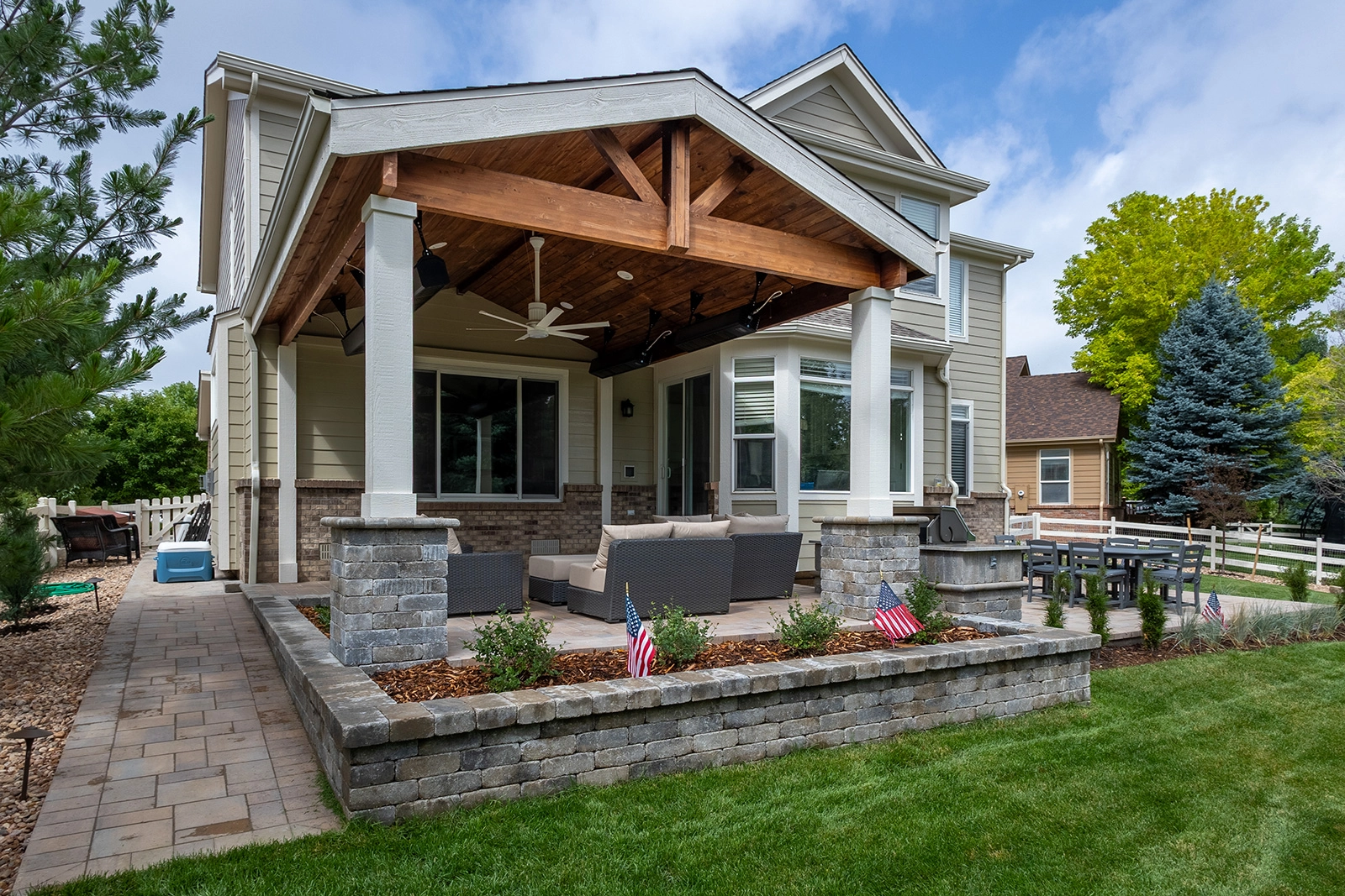 Curved paver patio with steps leading to a covered patio and stone planters